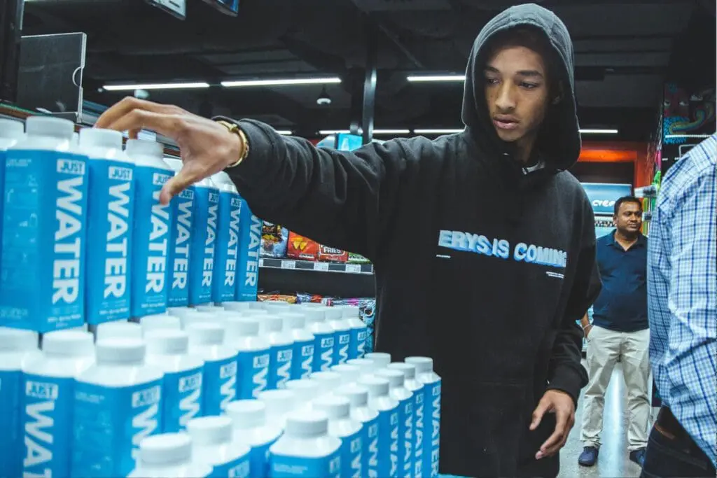 Jaden Smith arranging Just Water bottles in a store display