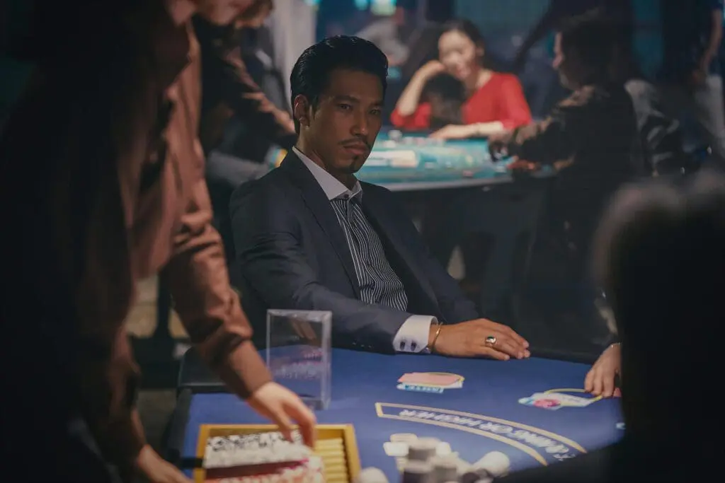 Actor in dim casino setting with tense expression