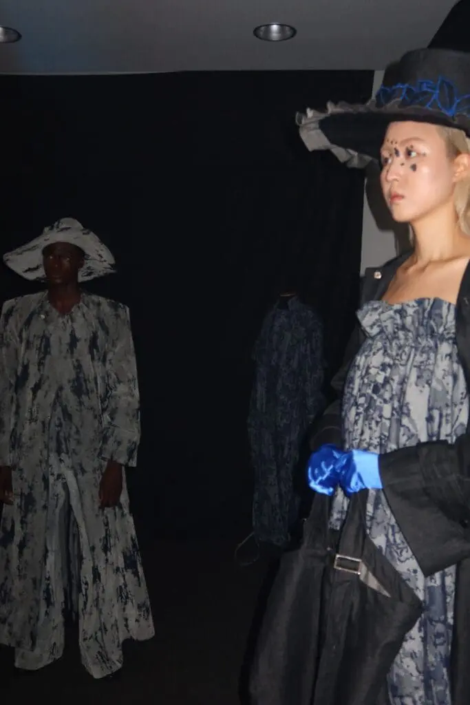 Avant-garde models in wide hats under dark lighting from Victor Hart Defiant show