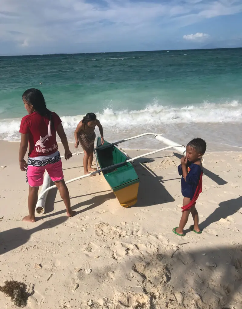 Children by a small boat on a tropical beach