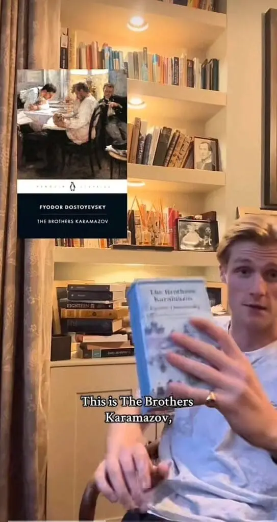 reader shows a book to camera in front of shelves