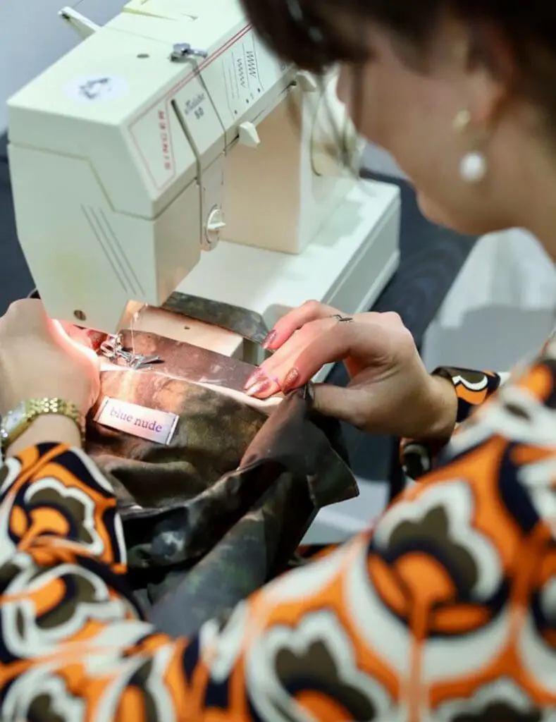 Close-up of sewing machine stitching textured bag
