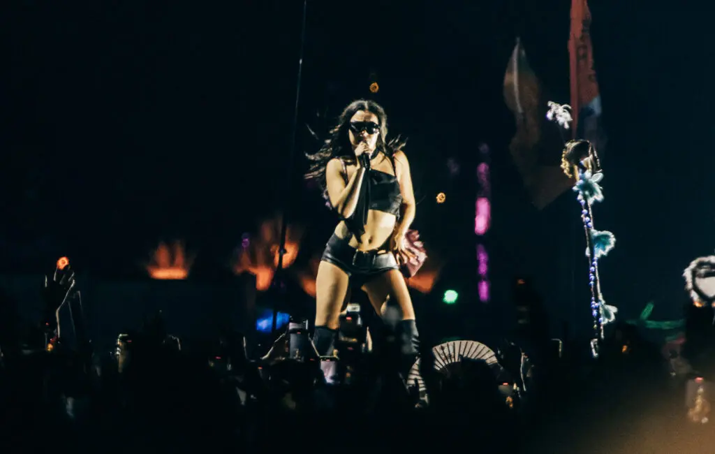 Pop concert stage shot with singer in black and crowd phones