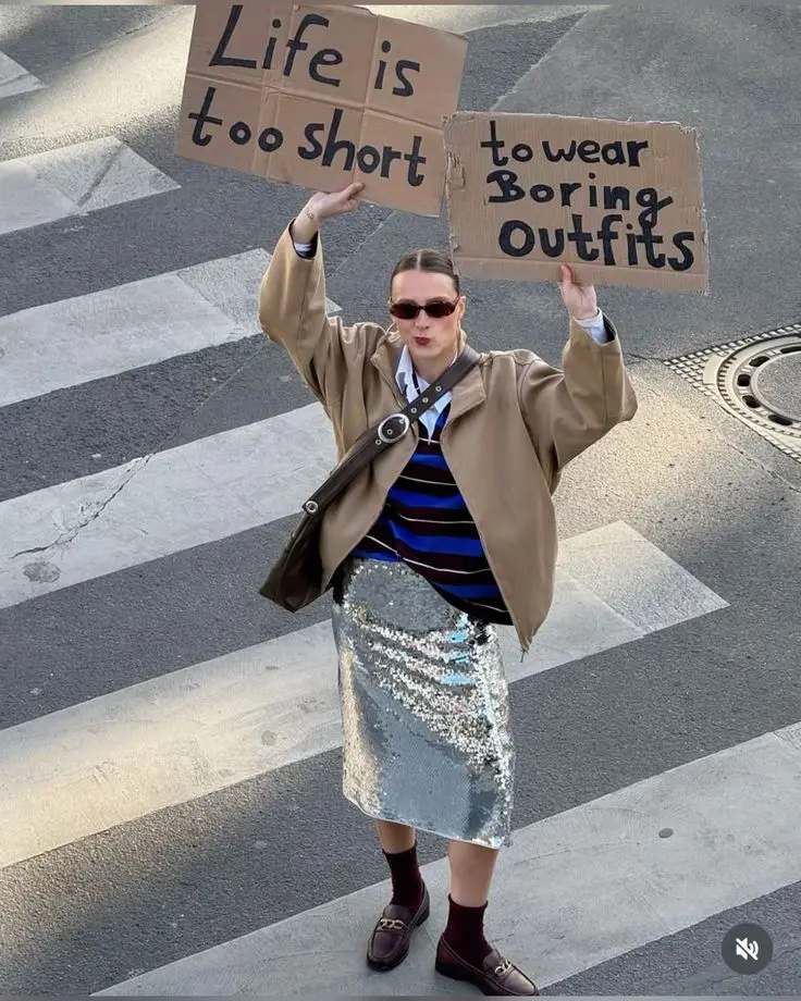 Street style in sequin skirt holding anti-boring outfit signs