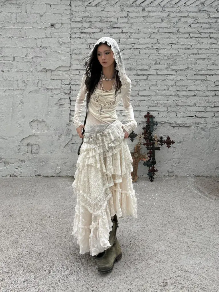 Woman in lace veil dress with layered necklaces and boots