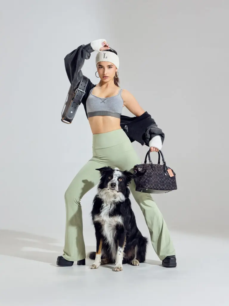 Leyla Ucar sporty street style in sage flared leggings, white beanie, handbag, dog