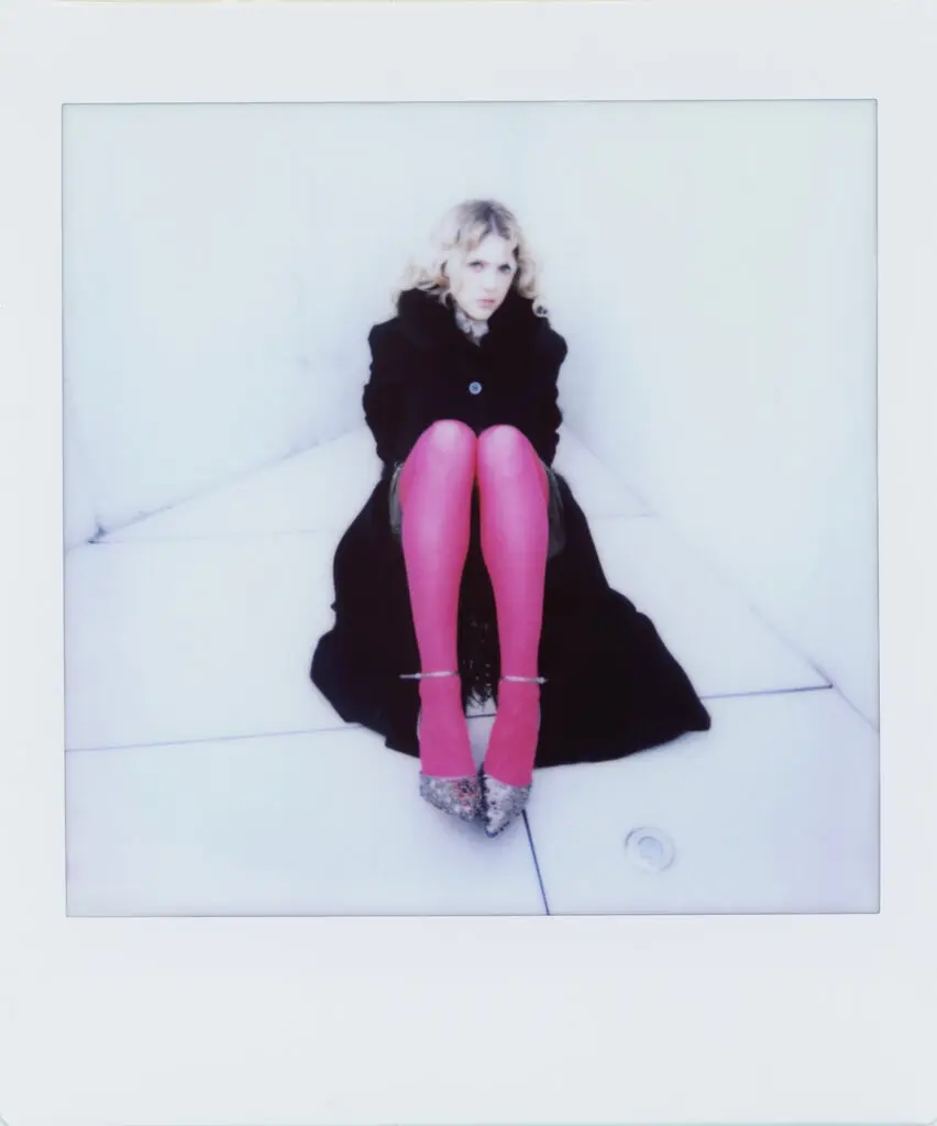 Carson Allen Polaroid in black coat and heels