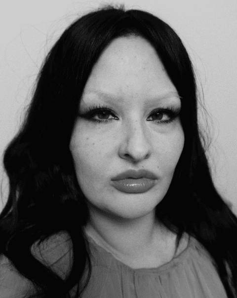 Monochrome portrait of Bea Sweet with bleached brows, dramatic lashes, and gloss lips