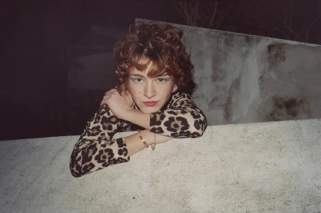 Night portrait over concrete wall, leopard-print top, direct gaze